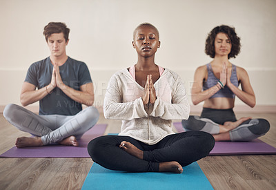 Buy stock photo Full length shot of a diverse group of yogis sitting together and meditating after an indoor yoga session
