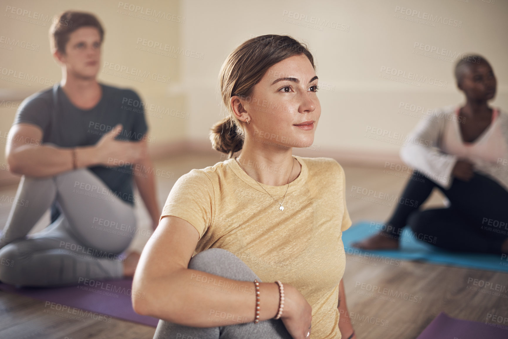 Buy stock photo Cropped shot of a diverse group of yogis holding a spinal half twist pose during an indoor yoga session