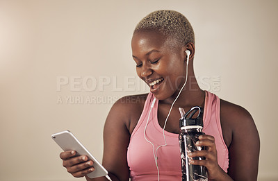 Buy stock photo Cropped shot of an attractive young woman sitting and wearing earphones while listening to music through her cellphone