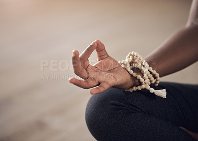 Buy stock photo Cropped shot of an unrecognizable woman sitting indoors alone and meditating with her hand in a gyan mudra