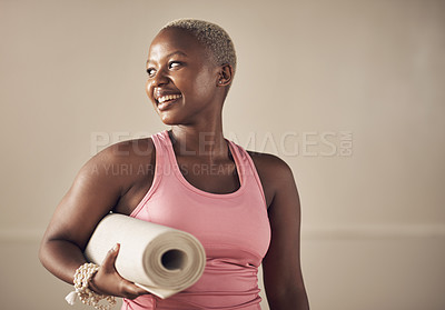 Buy stock photo Cropped shot of an attractive young woman standing alone and holding her yoga mat before an indoor yoga session