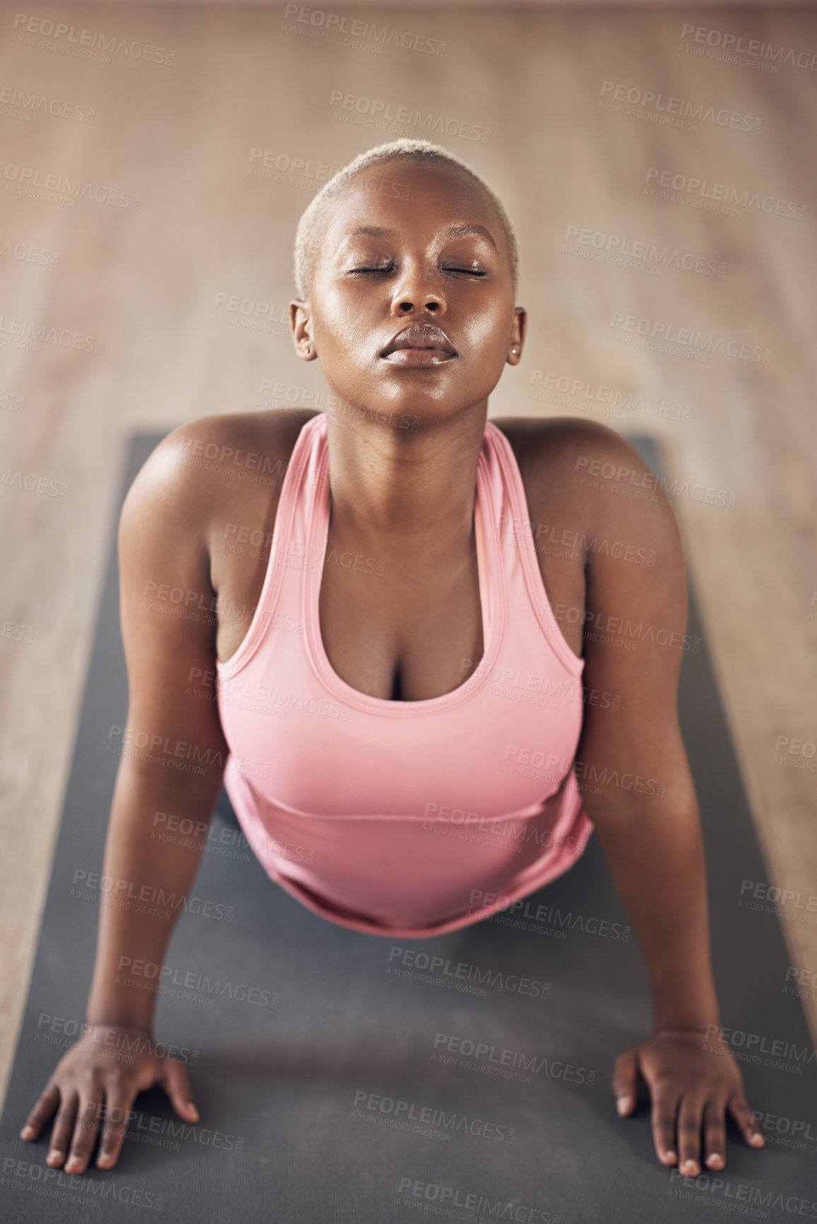 Buy stock photo Cropped shot of an attractive young woman holding an upward facing dog pose during an indoor yoga session alone