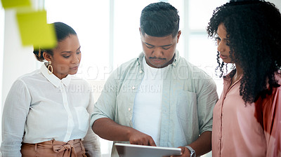 Buy stock photo Shot of a group of young businesspeople using a digital tablet during a brainstorming session in a modern office