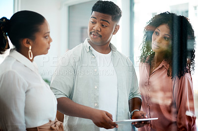Buy stock photo Shot of a group of young businesspeople using a digital tablet during a discussion in a modern office