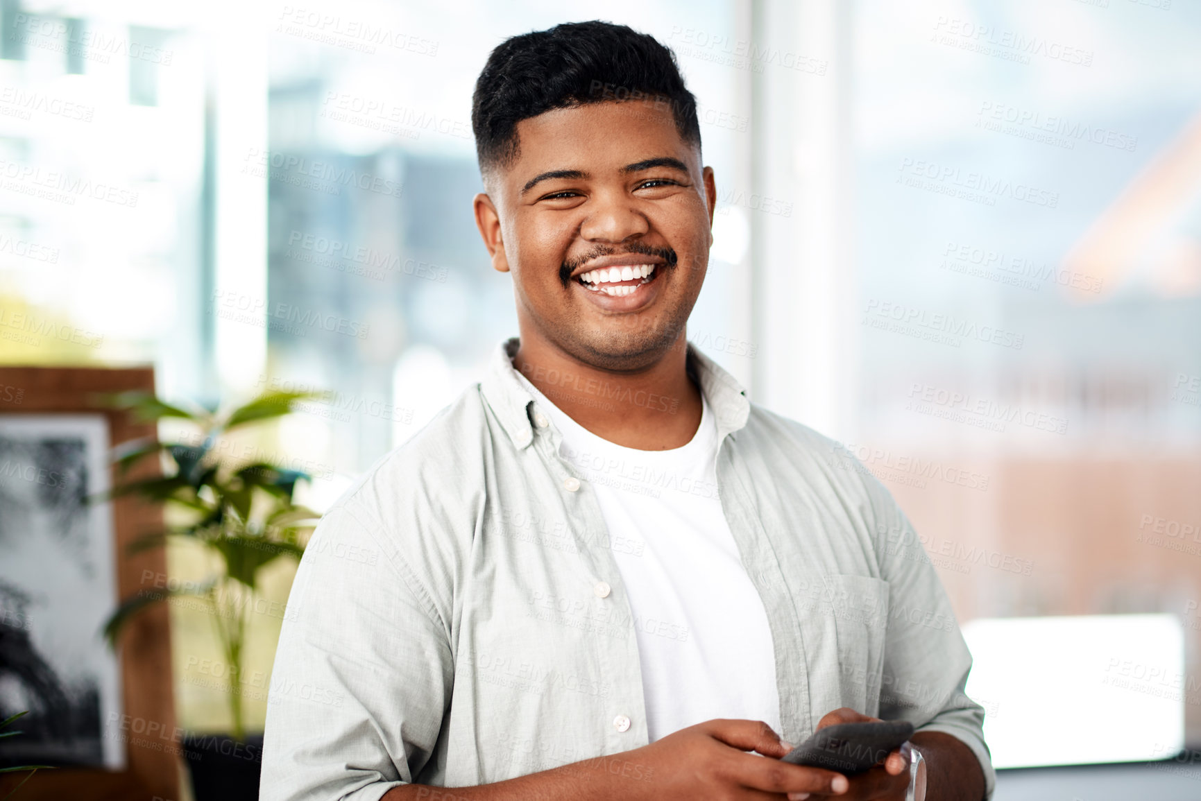 Buy stock photo Shot of a young businessman using a smartphone in a modern office