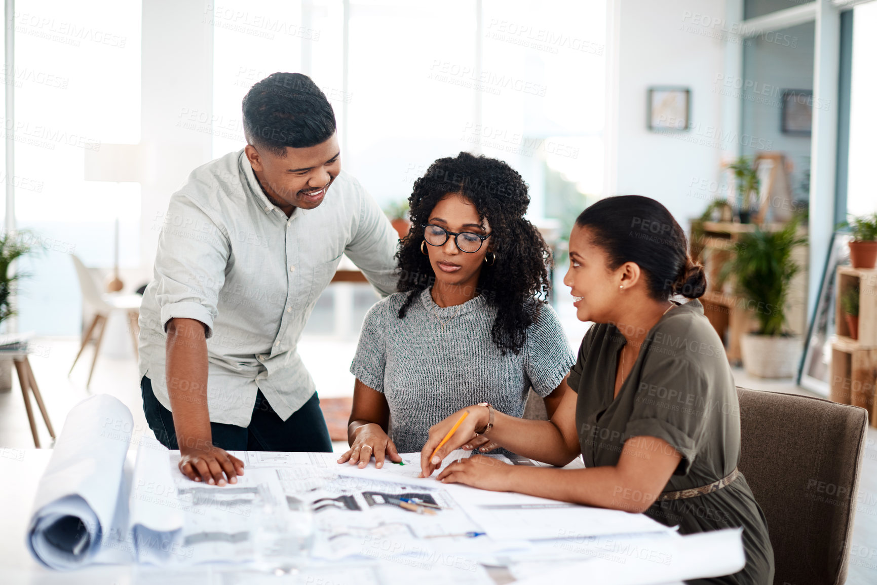 Buy stock photo Shot of a group of young businesspeople working on a blueprint in a modern office