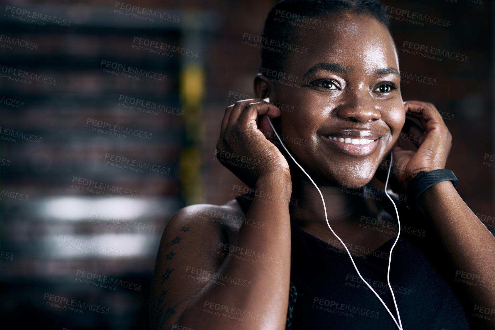 Buy stock photo Cropped shot of an attractive young female athlete listening to music while standing in the gym