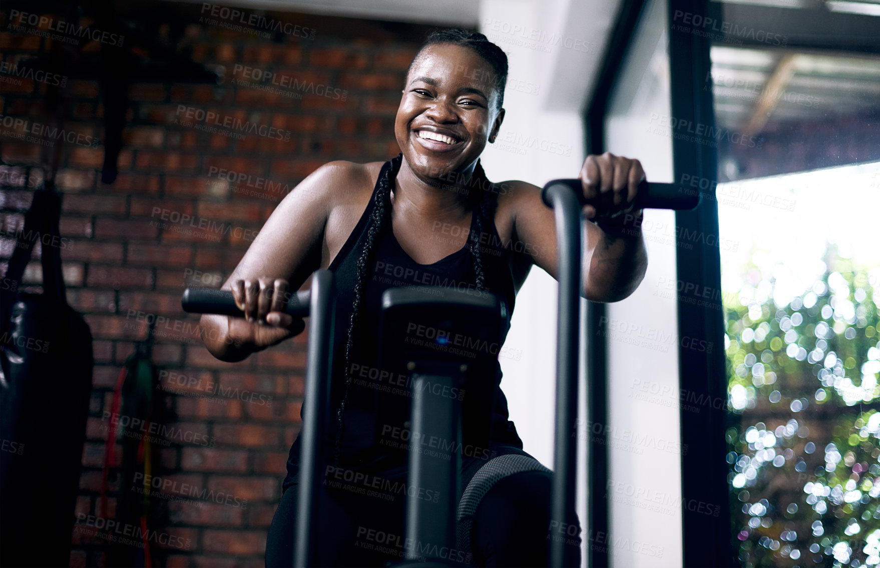 Buy stock photo Cropped portrait of an attractive young female athlete working out on an elliptical machine in the gym