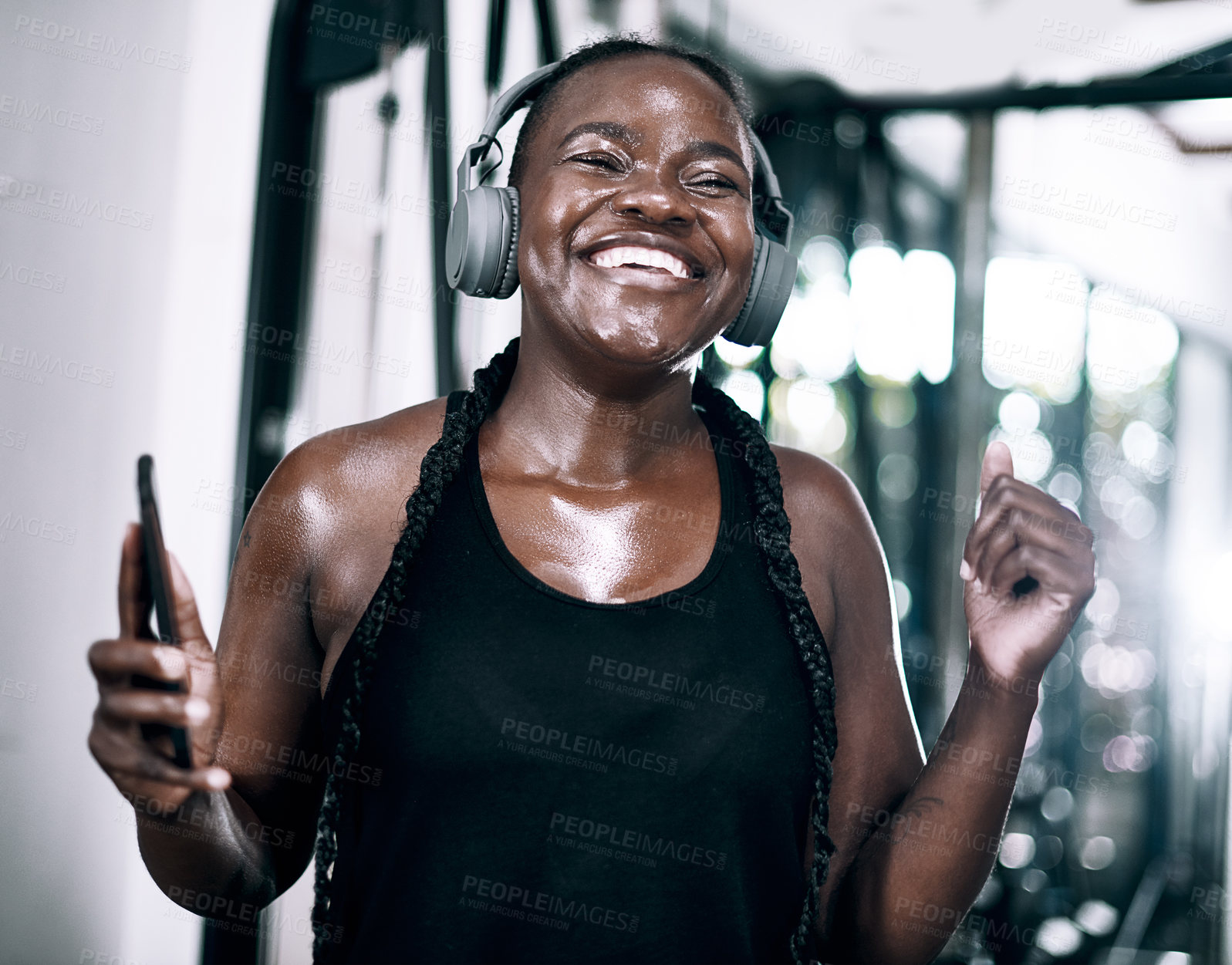 Buy stock photo Headphones, fitness and black woman in gym, smartphone and celebration for endurance, progress or challenge. African person, athlete or girl in wellness center, cellphone or excited with health goals