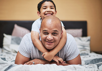 Buy stock photo Portrait of a cheerful little boy hanging on his father's back while hanging out in the bedroom at home during the day