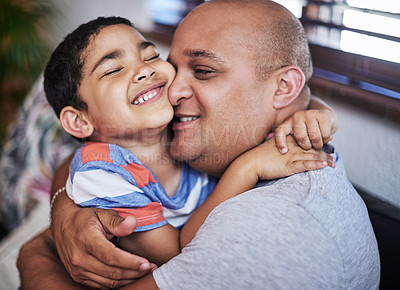 Buy stock photo Cropped shot of a cheerful young man hugging his son while being seated on a sofa at home during the day