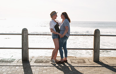 Buy stock photo Full length shot of an affectionate and happy young couple standing together on a promenade near the beach