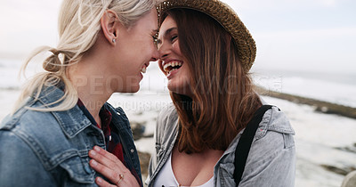 Buy stock photo Shot of an affectionate and happy young couple bonding and spending the day together outdoors near the beach