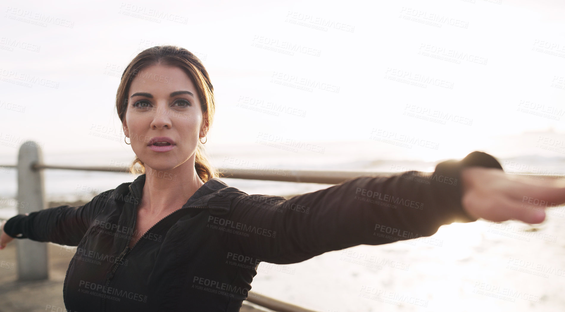 Buy stock photo Shot of a woman practising yoga on the promenade