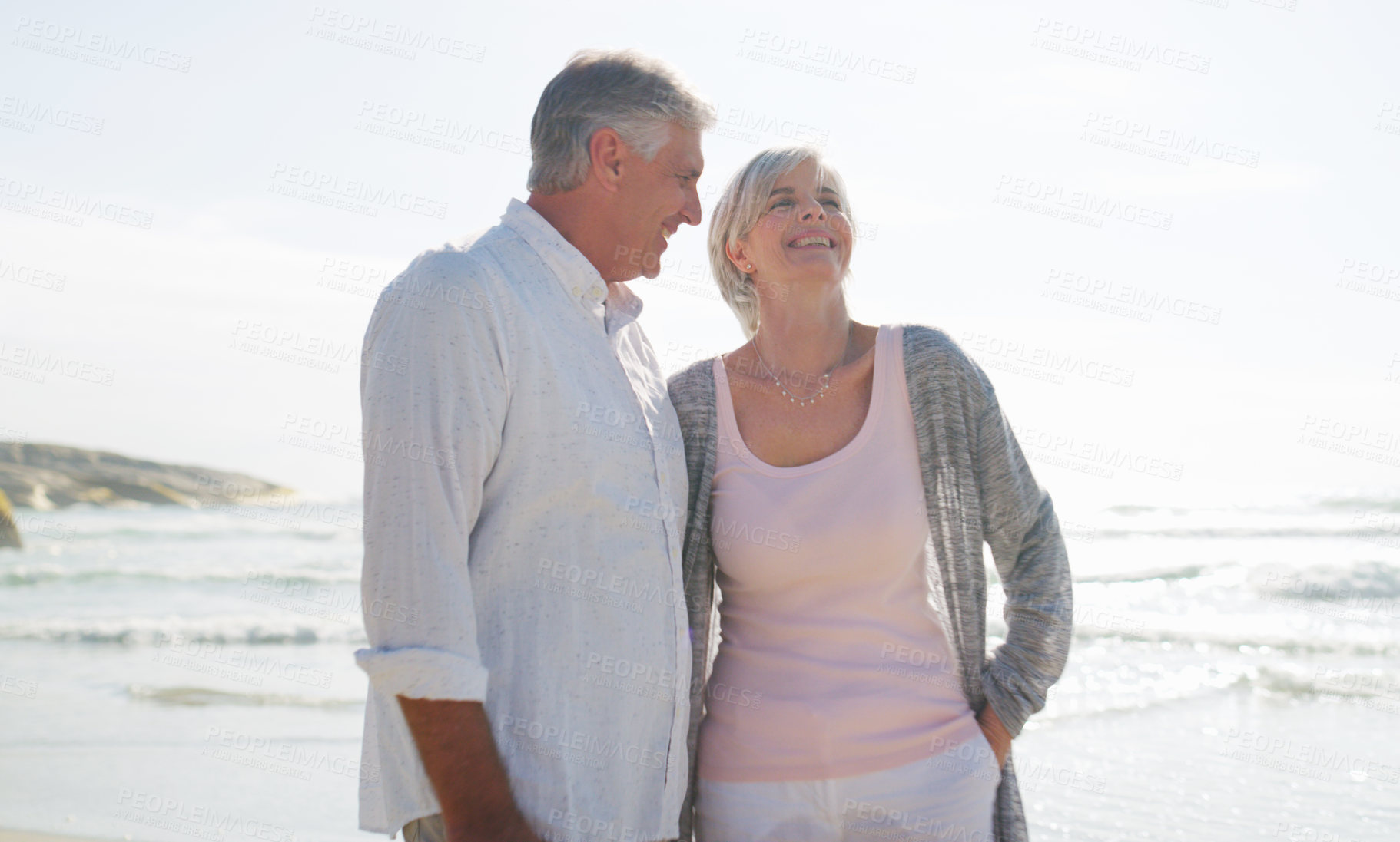Buy stock photo Cropped shot of an affectionate senior couple having a laugh together at the beach on a summer's day