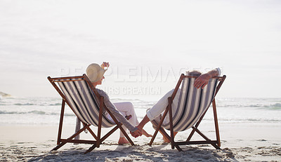 Buy stock photo Full length shot of an affectionate senior couple relaxing on loungers at the beach on a summer's day