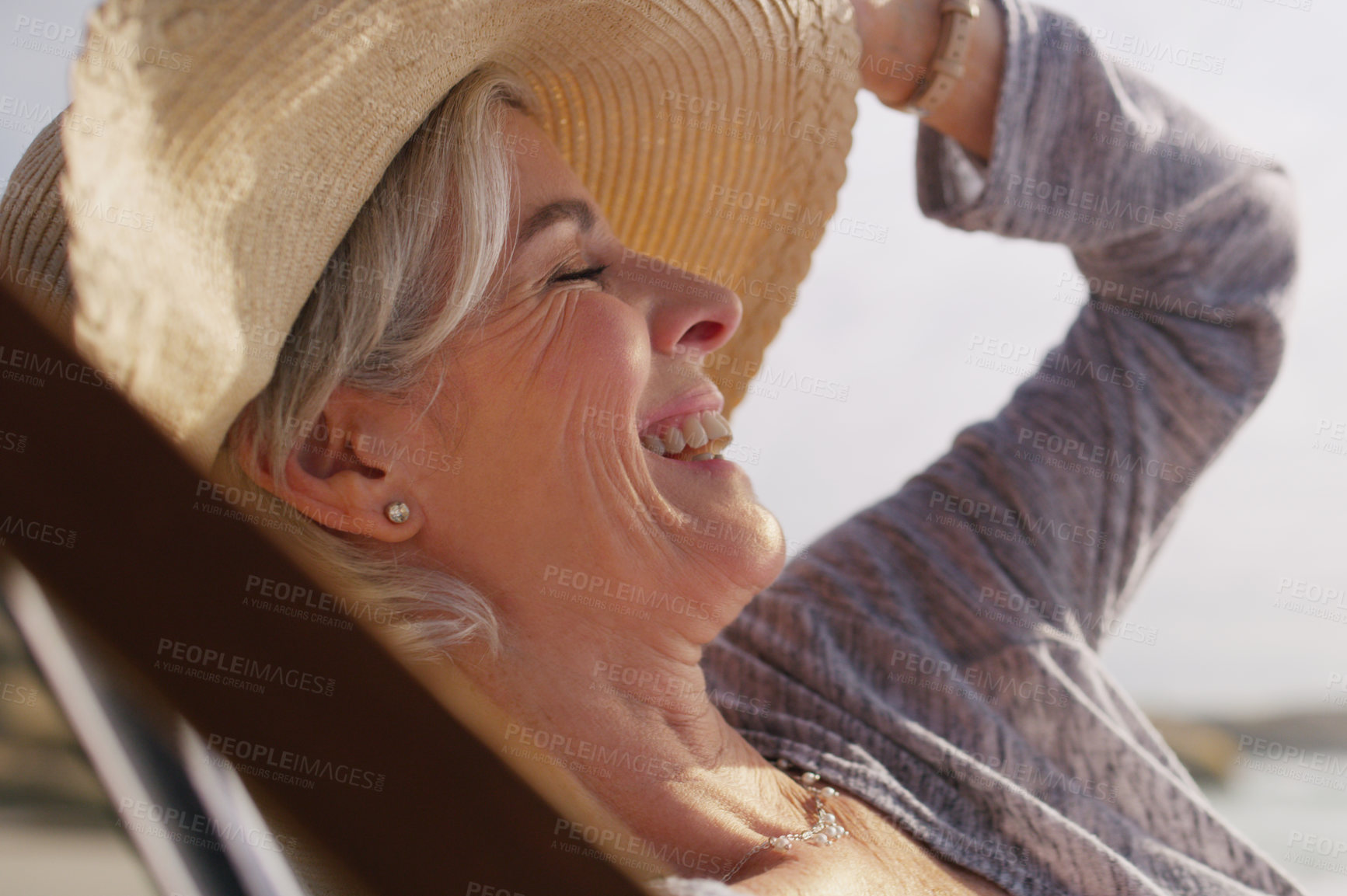 Buy stock photo Cropped shot of an attractive senior woman relaxing on a lounger on a summer's day at the beach