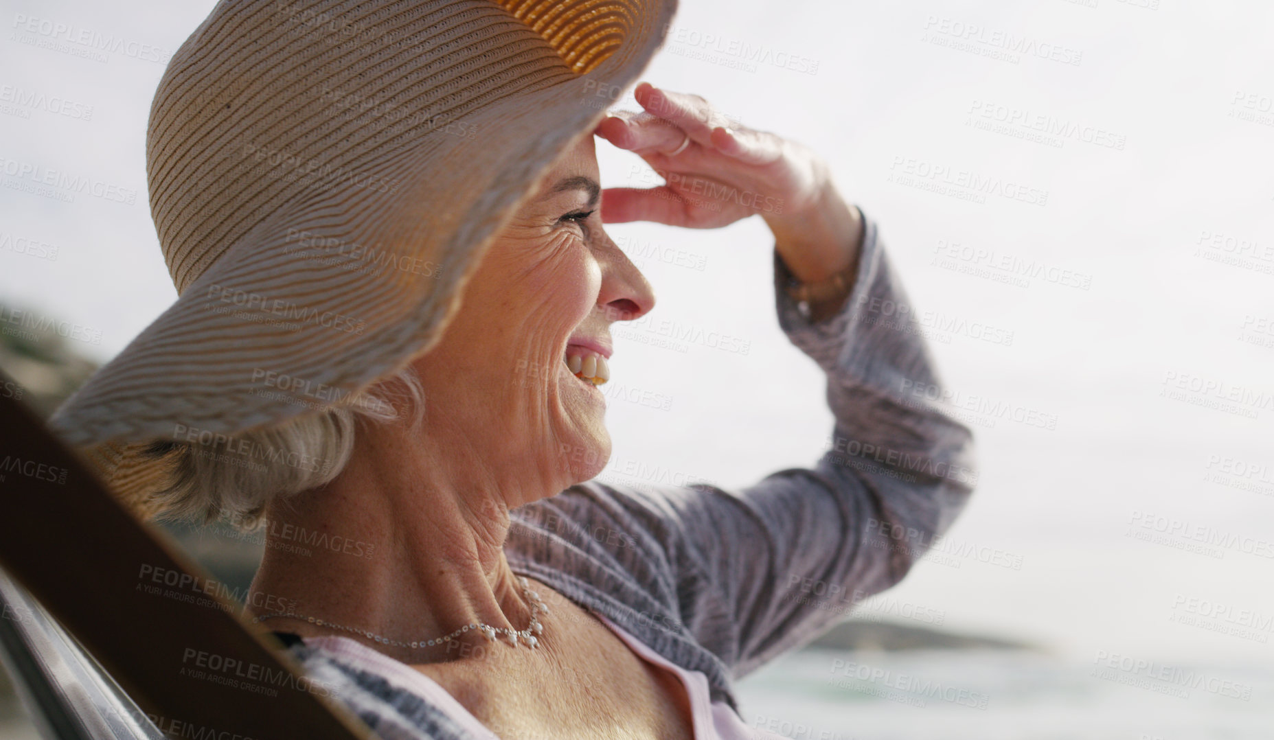 Buy stock photo Cropped shot of an attractive senior woman relaxing on a lounger on a summer's day at the beach