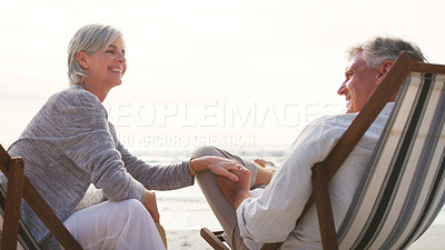 Buy stock photo Cropped shot of an affectionate senior couple relaxing on loungers at the beach on a summer's day