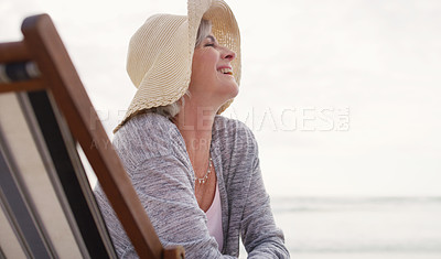 Buy stock photo Cropped shot of an attractive senior woman relaxing on a lounger on a summer's day at the beach