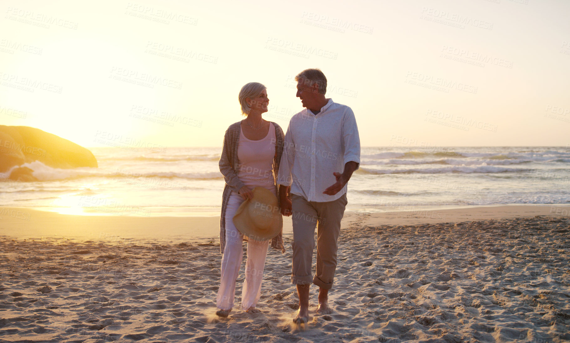 Buy stock photo Full length shot of an affectionate senior couple strolling at the beach at sunset