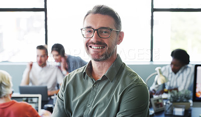 Buy stock photo Portrait of a confident mature businessman working in a modern office with his colleagues in the background