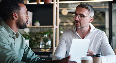 Buy stock photo Shot of two businessmen using a laptop and having a discussion in a modern office