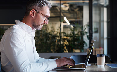 Buy stock photo Shot of a mature businessman using a laptop in a modern office