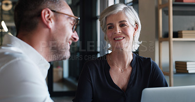 Buy stock photo Shot of a mature businessman and businesswoman using a laptop and having a discussion in a modern office