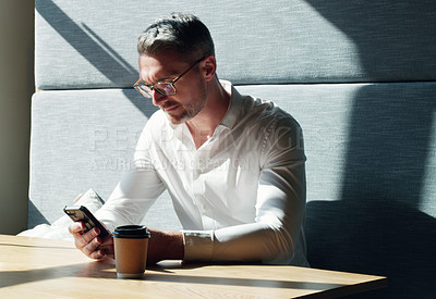 Buy stock photo Shot of a mature businessman using a smartphone in a modern office