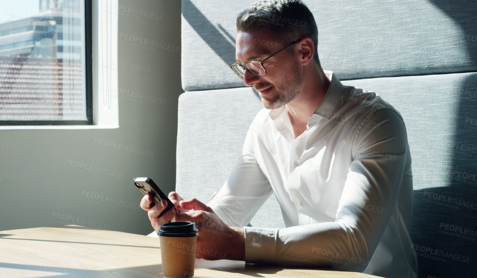 Buy stock photo Shot of a mature businessman using a smartphone in a modern office