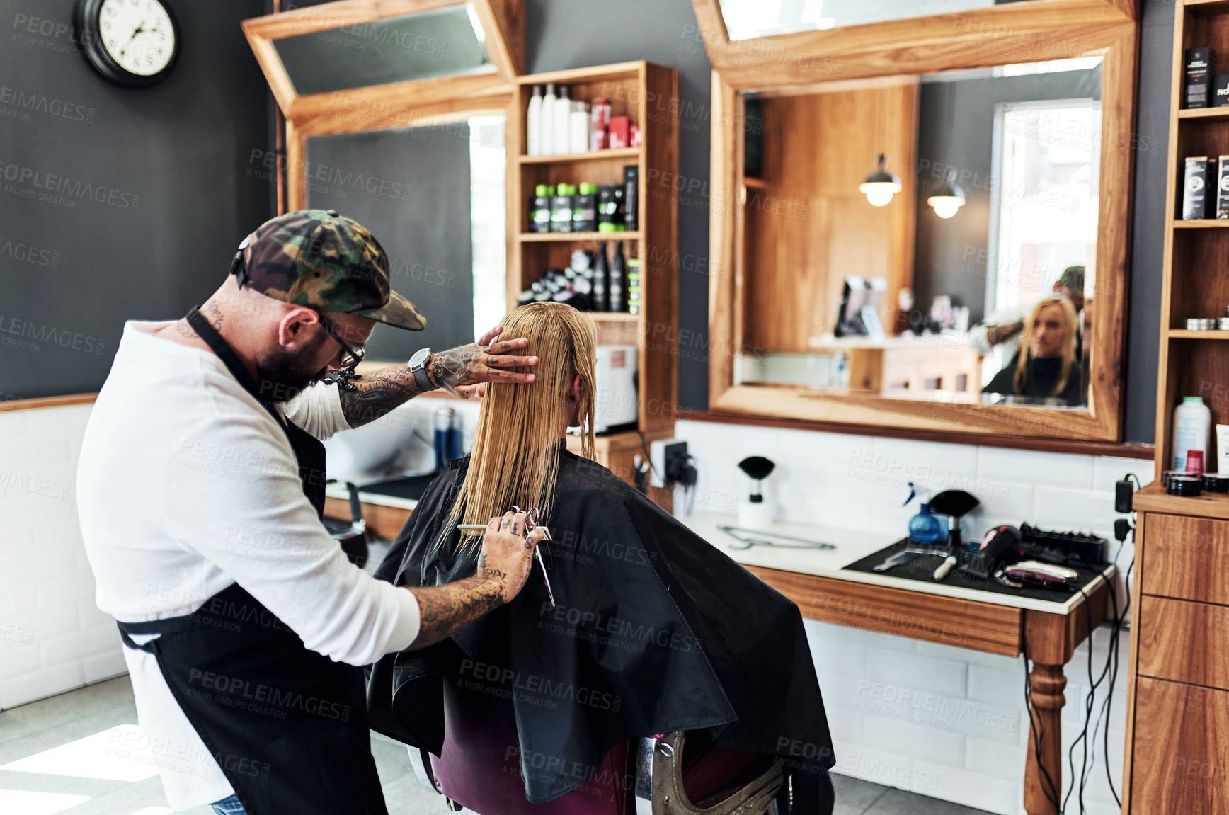 Buy stock photo Cropped shot of a male hairdresser styling a woman's hair inside a salon