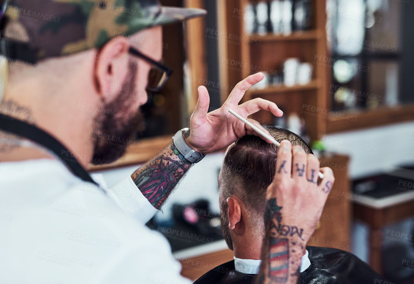 Buy stock photo Cropped shot of a handsome young barber giving a client a haircut inside his barbershop