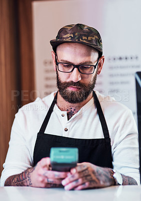 Buy stock photo Cropped shot of a handsome young barber using a card machine inside his barbershop