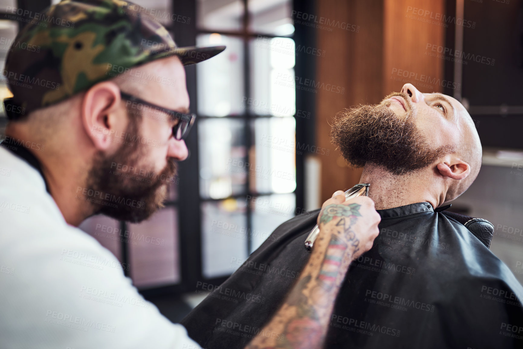 Buy stock photo Cropped shot of a handsome young barber trimming and lining up a clients beard inside his barbershop