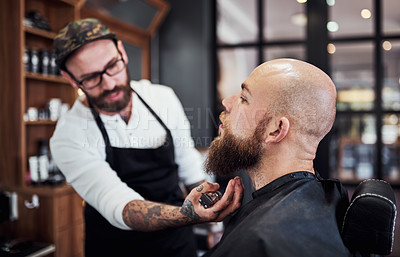 Buy stock photo Cropped shot of a handsome young barber trimming and lining up a clients beard inside his barbershop