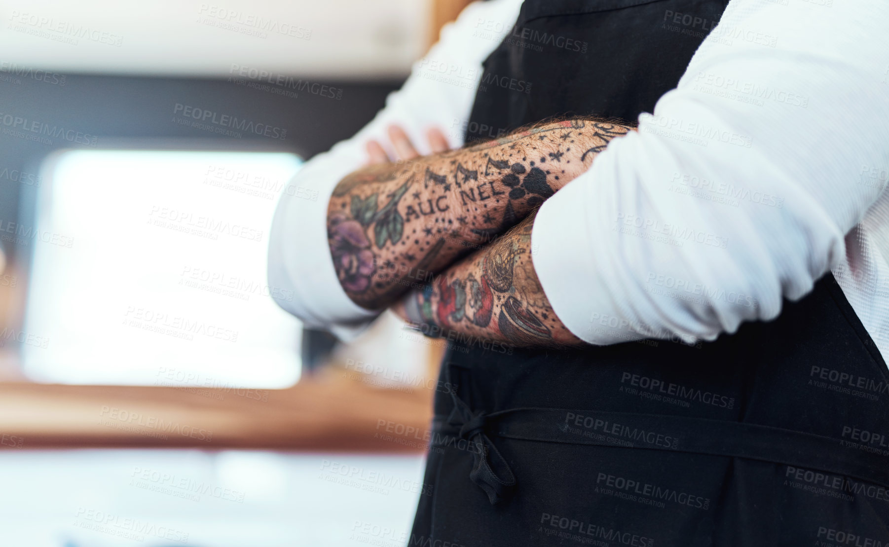 Buy stock photo Cropped shot of an unrecognizable tattooed barber posing with his arms folded inside a barbershop