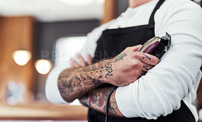 Buy stock photo Cropped shot of an unrecognizable tattooed barber posing with his arms folded inside a barbershop