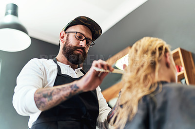 Buy stock photo Cropped shot of a handsome male hairdresser styling and treating a woman's hair inside a salon