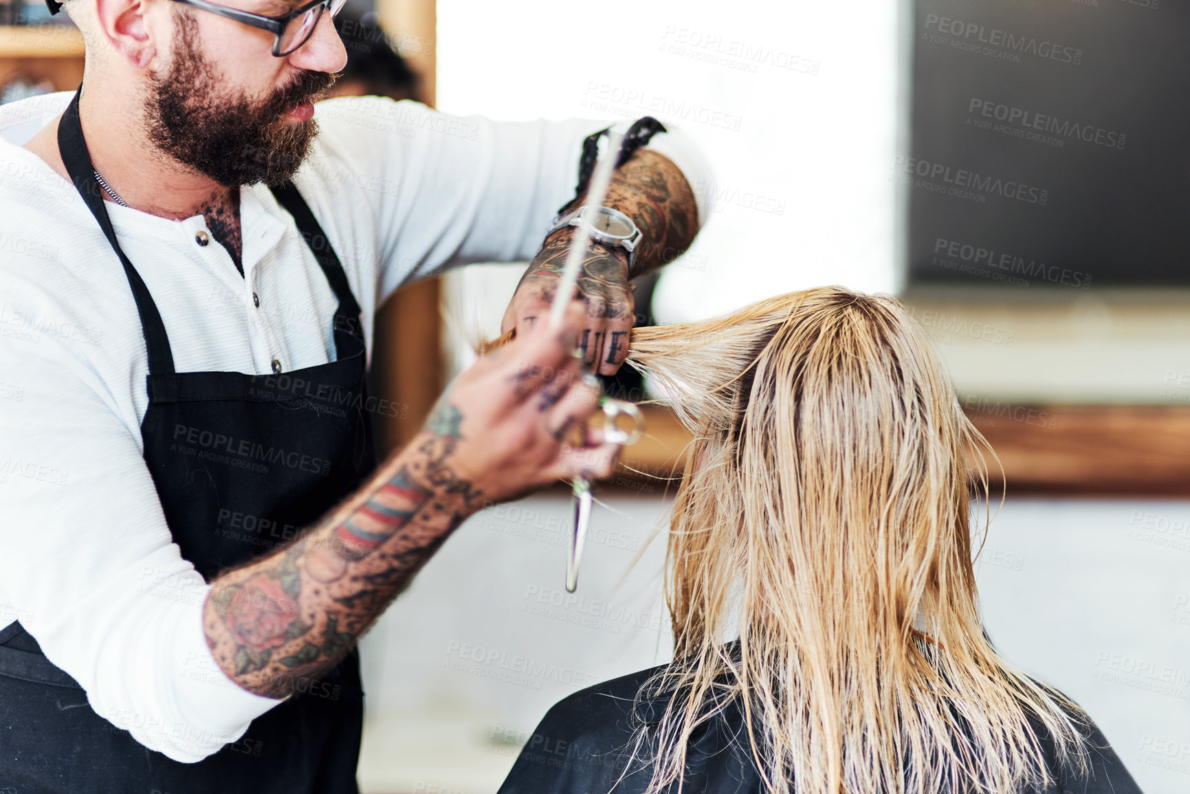 Buy stock photo Cropped shot of a handsome male hairdresser styling and treating a woman's hair inside a salon