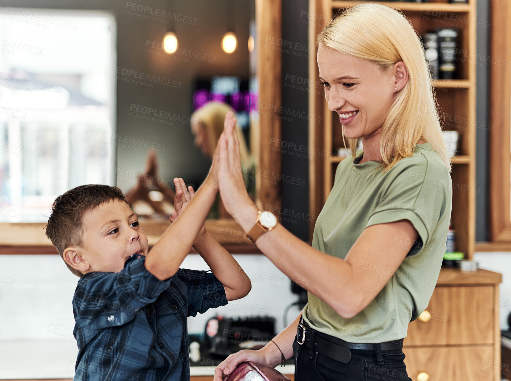 Buy stock photo Cropped shot of an adorable little boy giving his hairdresser a high five inside a salon