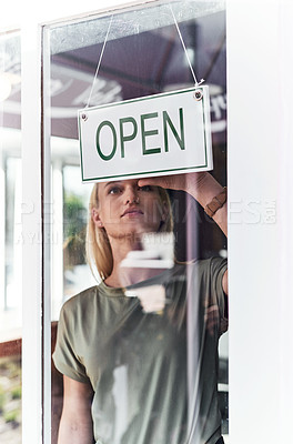 Buy stock photo Cropped shot of an attractive young hairdresser hanging up an open sign on the window of her salon
