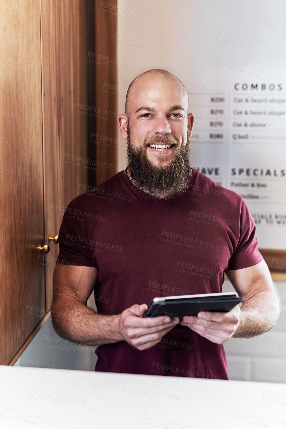 Buy stock photo Portrait of a handsome young barber using a digital tablet while working inside his barbershop