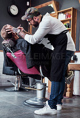 Buy stock photo Full length shot of a handsome young barber trimming and lining up a clients beard inside a barbershop