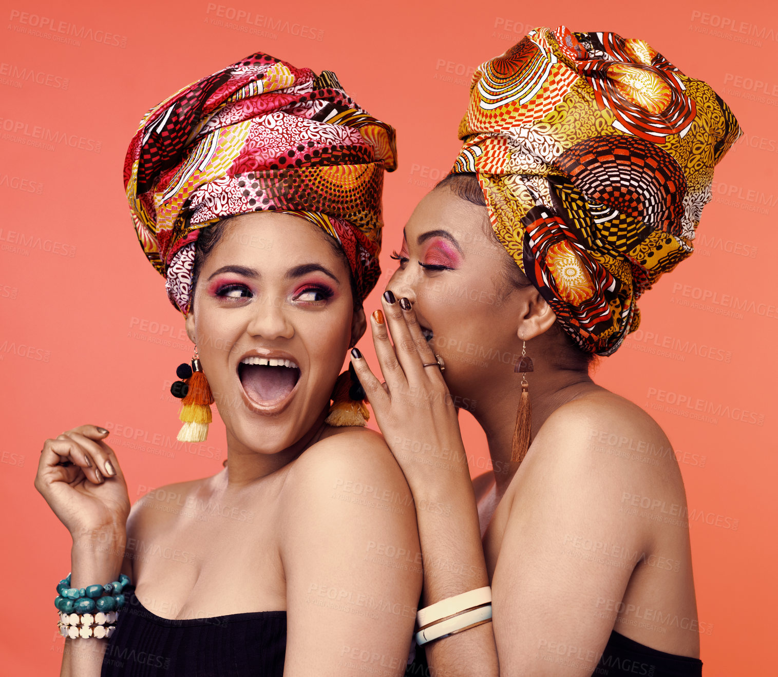 Buy stock photo Studio shot of two attractive young women wearing traditional  African head wraps posing together against an orange background