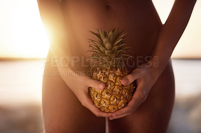 Buy stock photo Cropped shot of an unrecognizable naked woman holding a pineapple outdoors at sunset