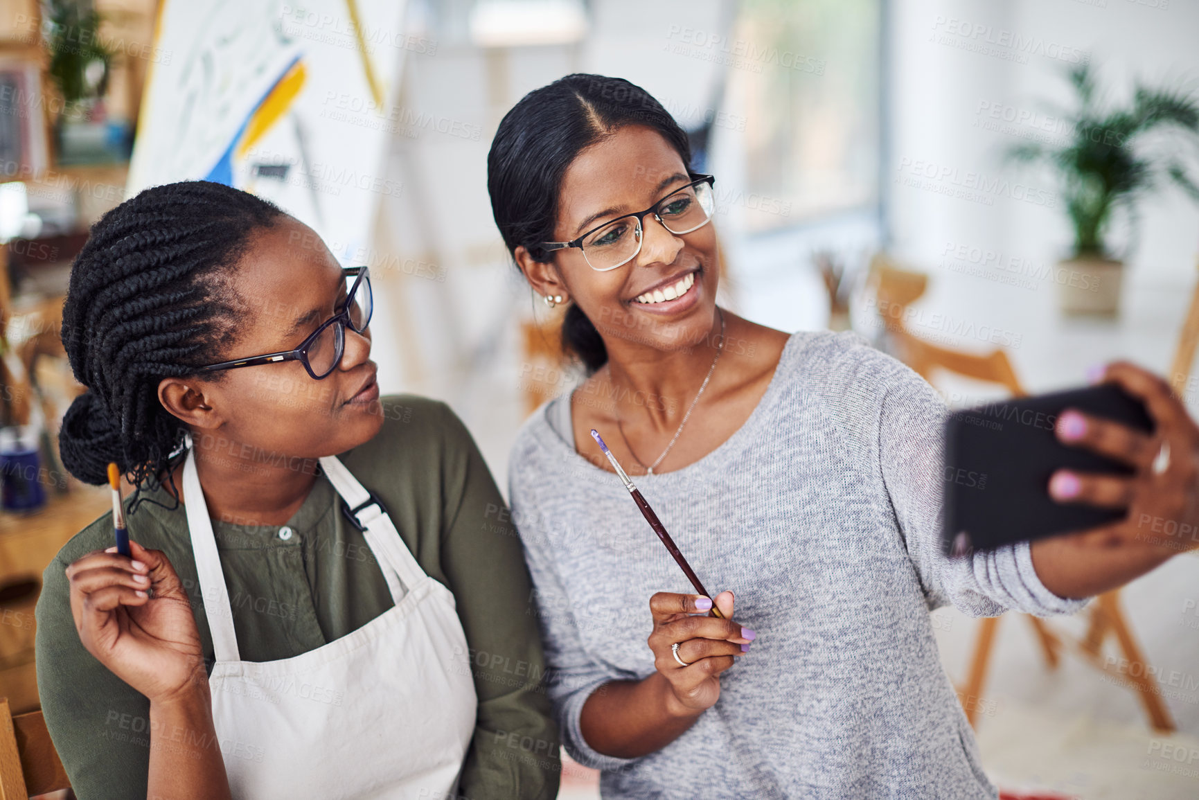 Buy stock photo Cropped shot of two young women taking a selfie while painting in a art studio