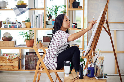 Buy stock photo Shot of a beautiful young woman working on a painting in a art studio