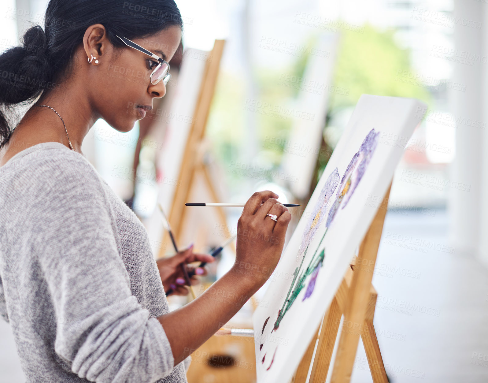 Buy stock photo Shot of a beautiful young woman working on a painting in a art studio