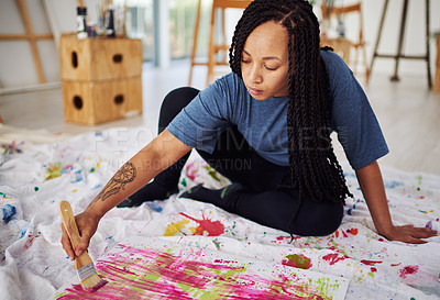 Buy stock photo Shot of a young woman sitting on the floor while painting in a art studio